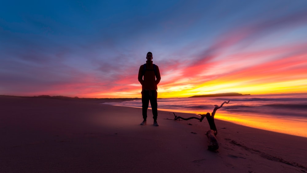 man standing on a beach during sunset