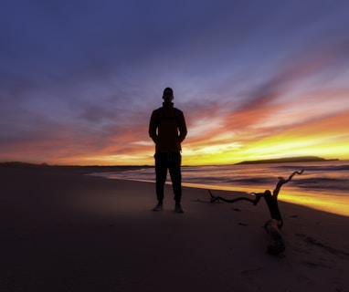 man standing on a beach during sunset