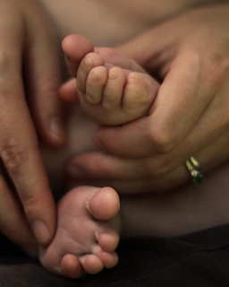 A close-up of hands gently holding a baby’s tiny feet, symbolizing trust and care.
