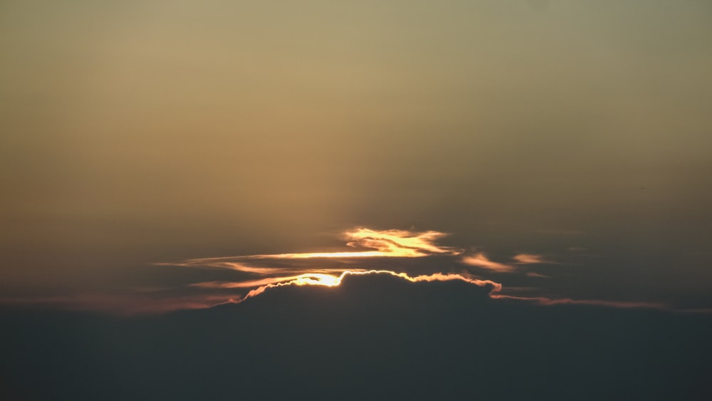 the sun is setting behind a cloud in the sky