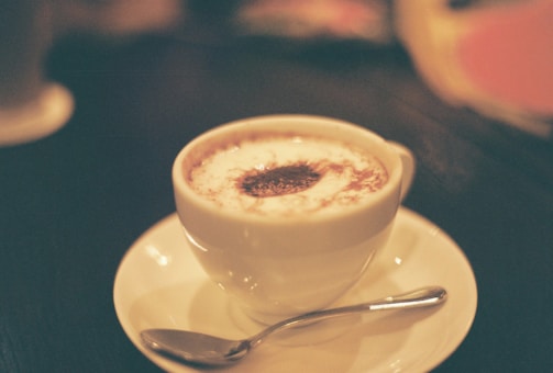 A creamy cappuccino topped with frothy milk and a sprinkle of cinnamon in a cozy café setting.