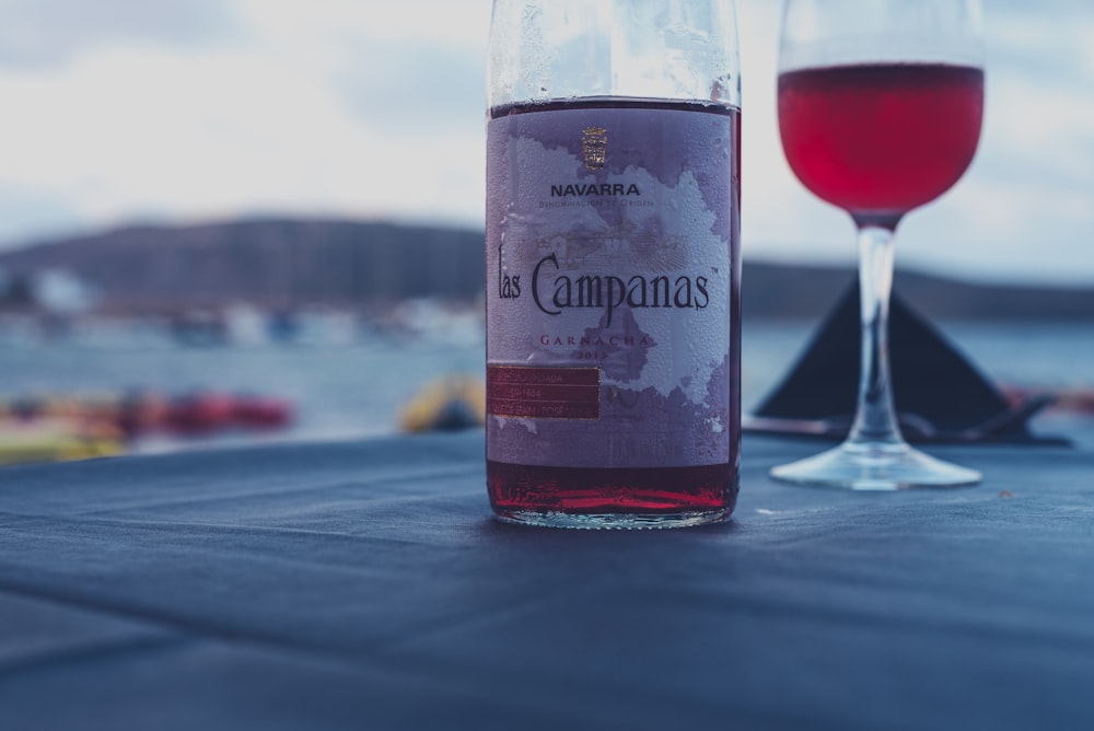 Botella de vino tinto Campanas junto a copa de vino