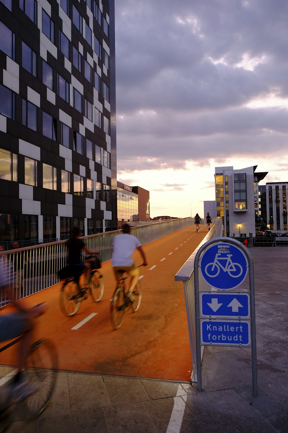 Personas en bicicleta dentro del carril bici junto a un rascacielos