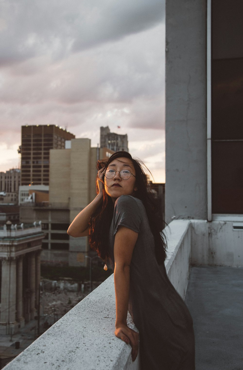 An Asian girl leaning over a balcony ledge.