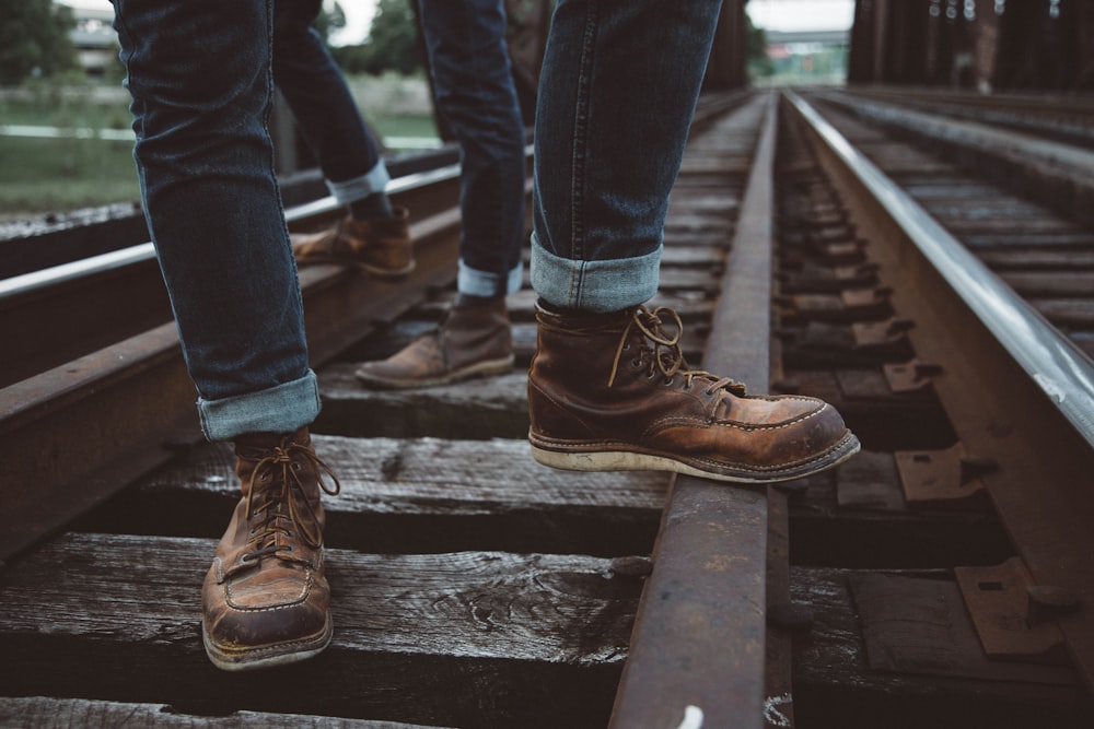 Deux personnes portant des chaussures brunes debout dans le rail du train