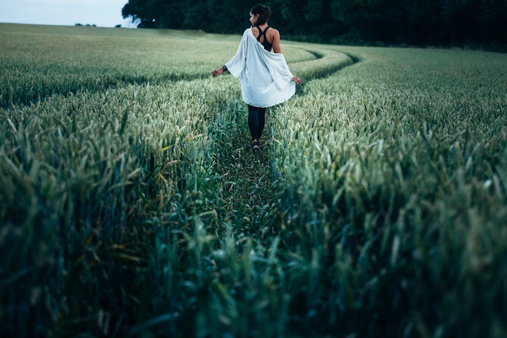femme marchant sur un champ d’herbe