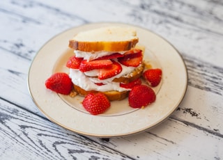 bread with cream and strawberry slices on plate