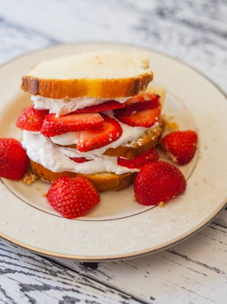 bread with cream and strawberry slices on plate