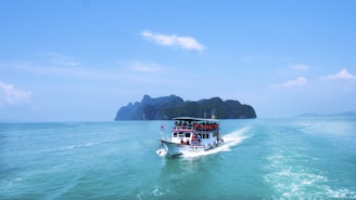 boat with peoples sailing on body of water with island background
