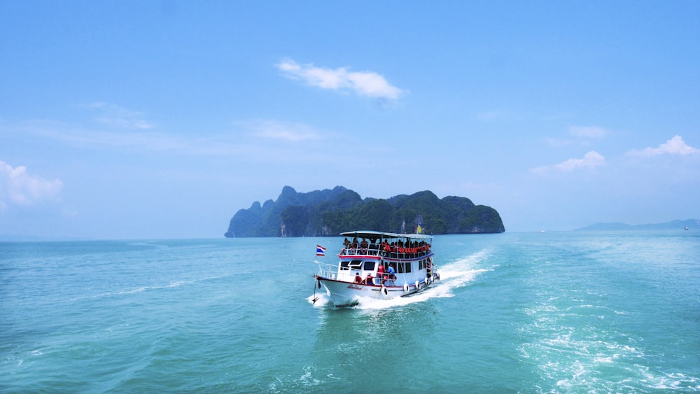 boat with peoples sailing on body of water with island background