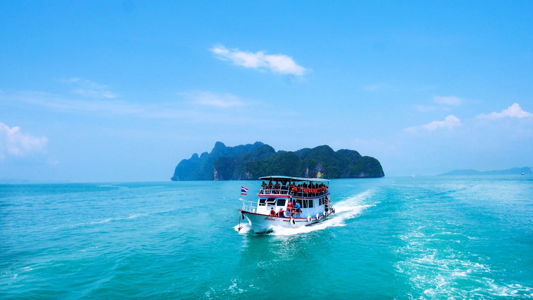 boat with peoples sailing on body of water with island background