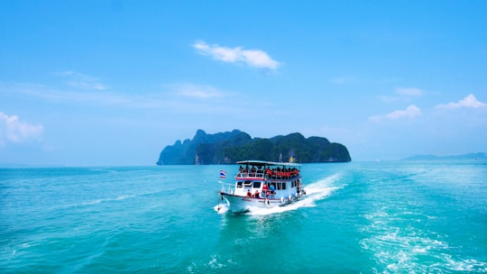 boat with peoples sailing on body of water with island background in Phang Nga Bay Thailand