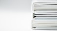 A stack of thick folders on a white surface