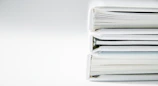 A stack of thick folders on a white surface