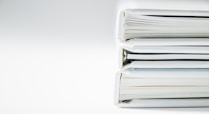 A stack of thick folders on a white surface