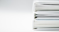 A stack of thick folders on a white surface