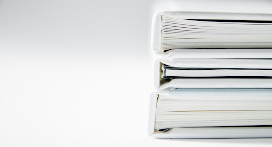 A stack of thick folders on a white surface
