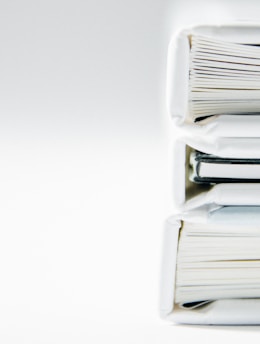 A stack of thick folders on a white surface