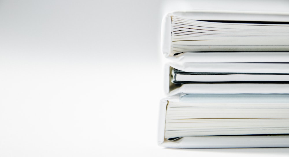 A stack of thick folders on a white surface