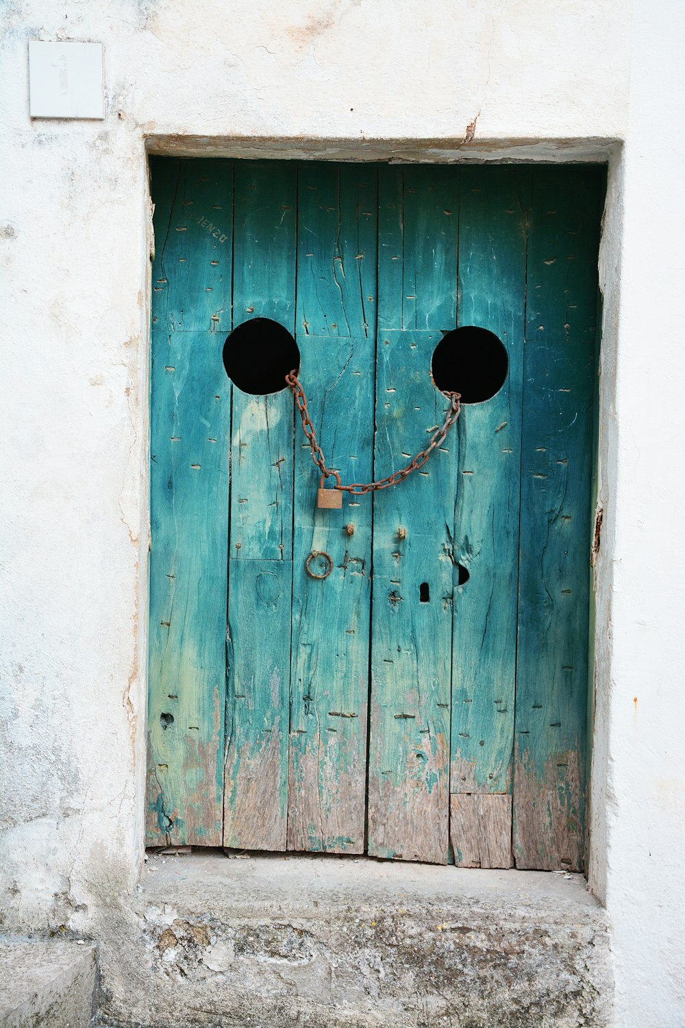회색 체인과 갈색 자물쇠가 있는 청록색 나무 문