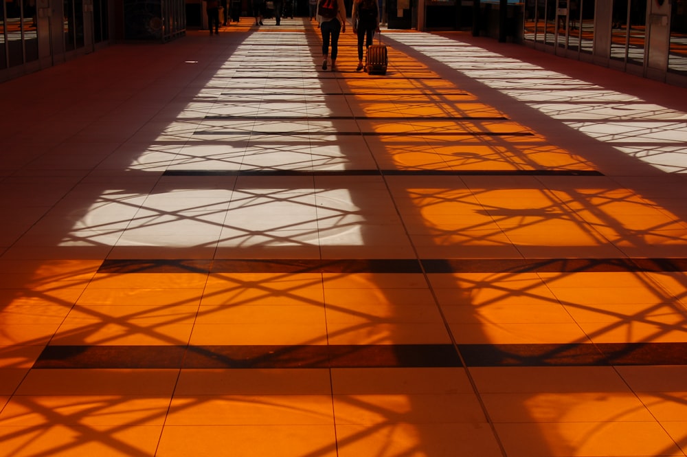 two person walking inside building with orange floor