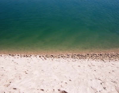 white sand near green calm body of water at daytime