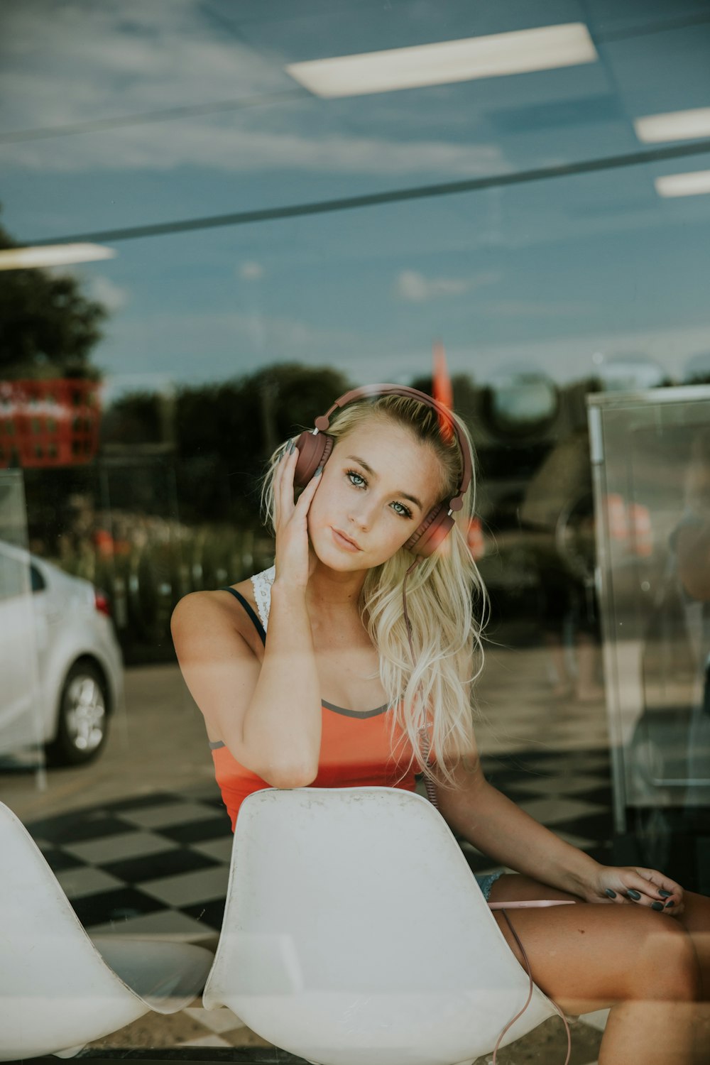 A reflection of a blonde woman in headphones behind a glass wall