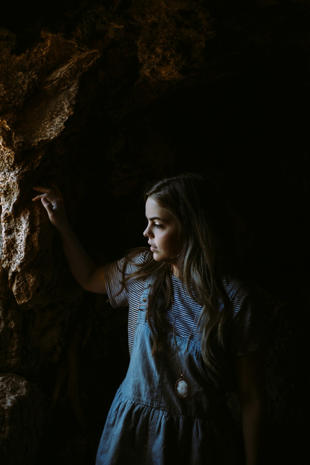 muchacha con vestido azul y blanco sosteniendo en rocas marrones