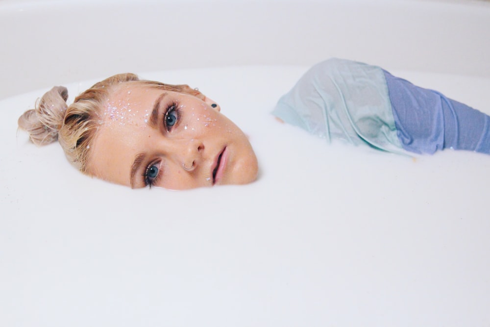 blonde hair woman in blue top on white liquid