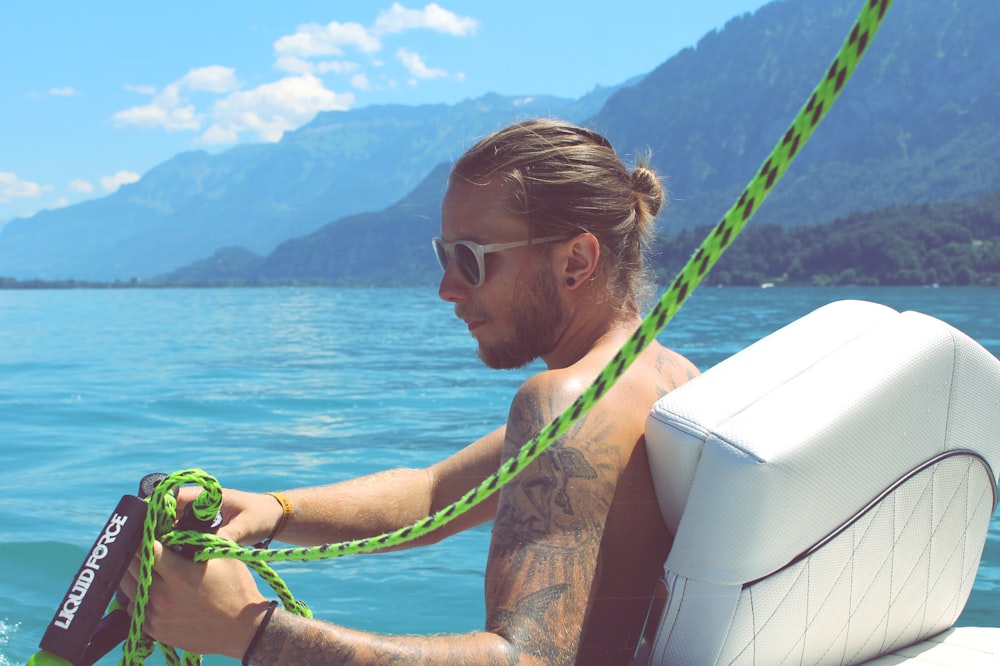 man holding black and green rope near body of water during daytime