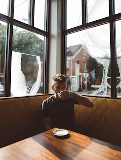 An upscale customer enjoying a quiet moment with a latte by the window, bathed in natural light and surrounded by elegant decor.