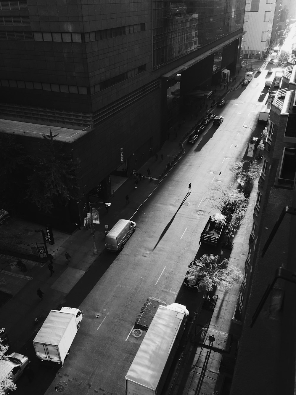 grayscale photo of person walking on road outside building