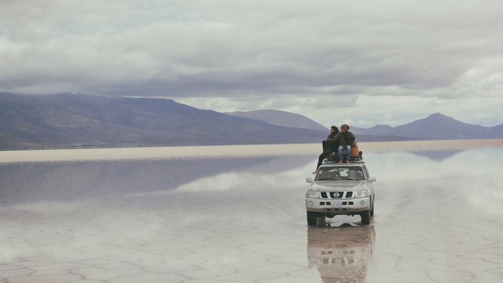 people on silver vehicle under gray sky during daytime