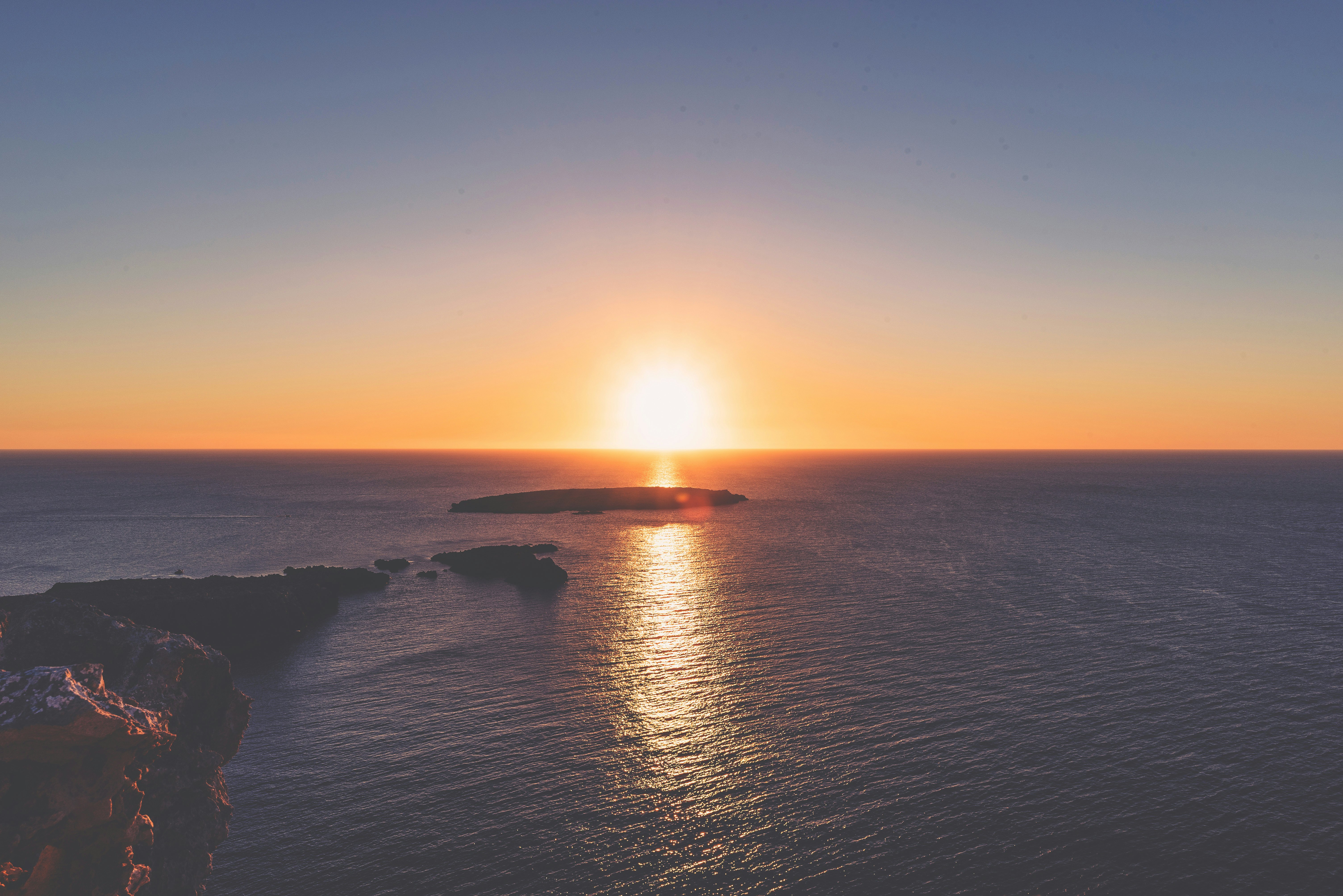 rock on body of water during sunset \