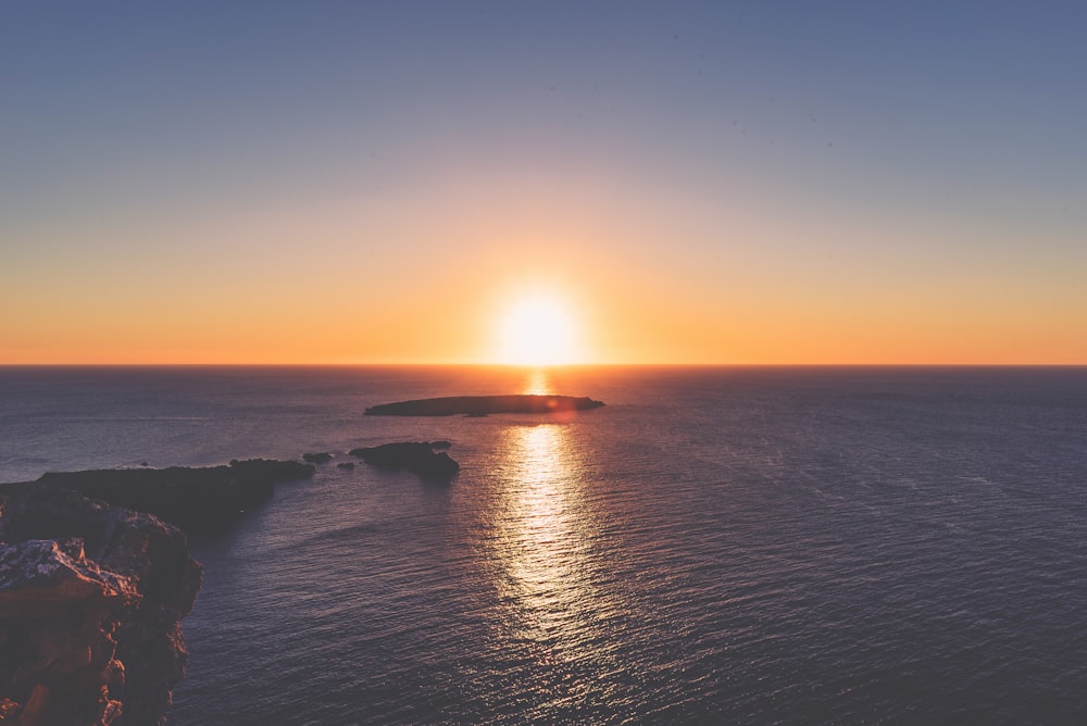 roca en el cuerpo de agua durante la puesta del sol \