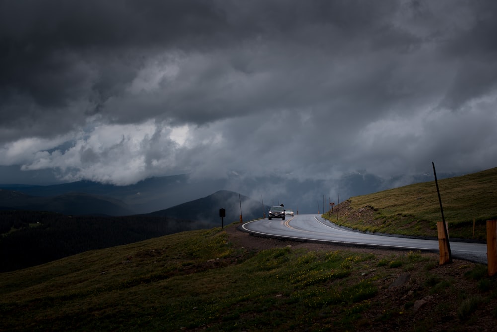 Auto nera sulla strada asfaltata grigia sotto il cielo nuvoloso