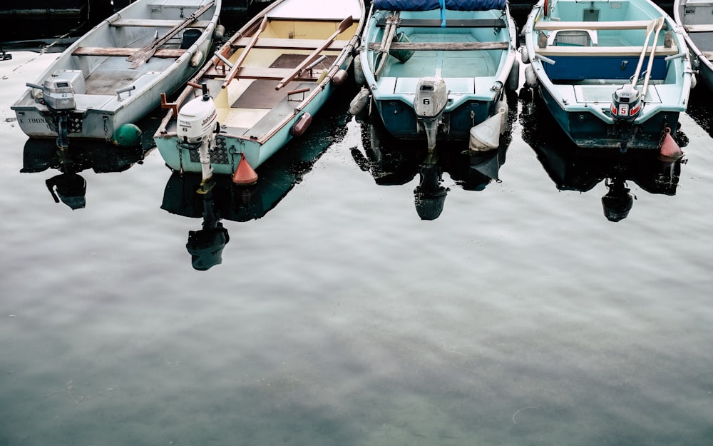 Quattro barche Jon bianche e blu su uno specchio d'acqua calmo