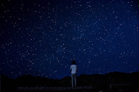 A person looking thoughtfully at the stars in a clear night sky