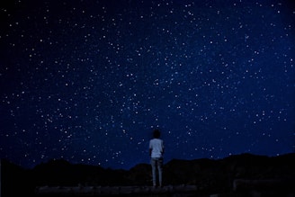 A person gazing at the night sky filled with stars and constellations.