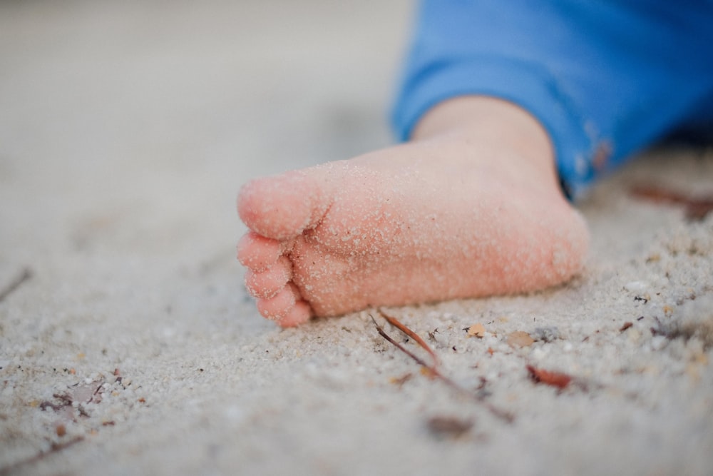 Fotografía de enfoque superficial del pie del niño pequeño con arena
