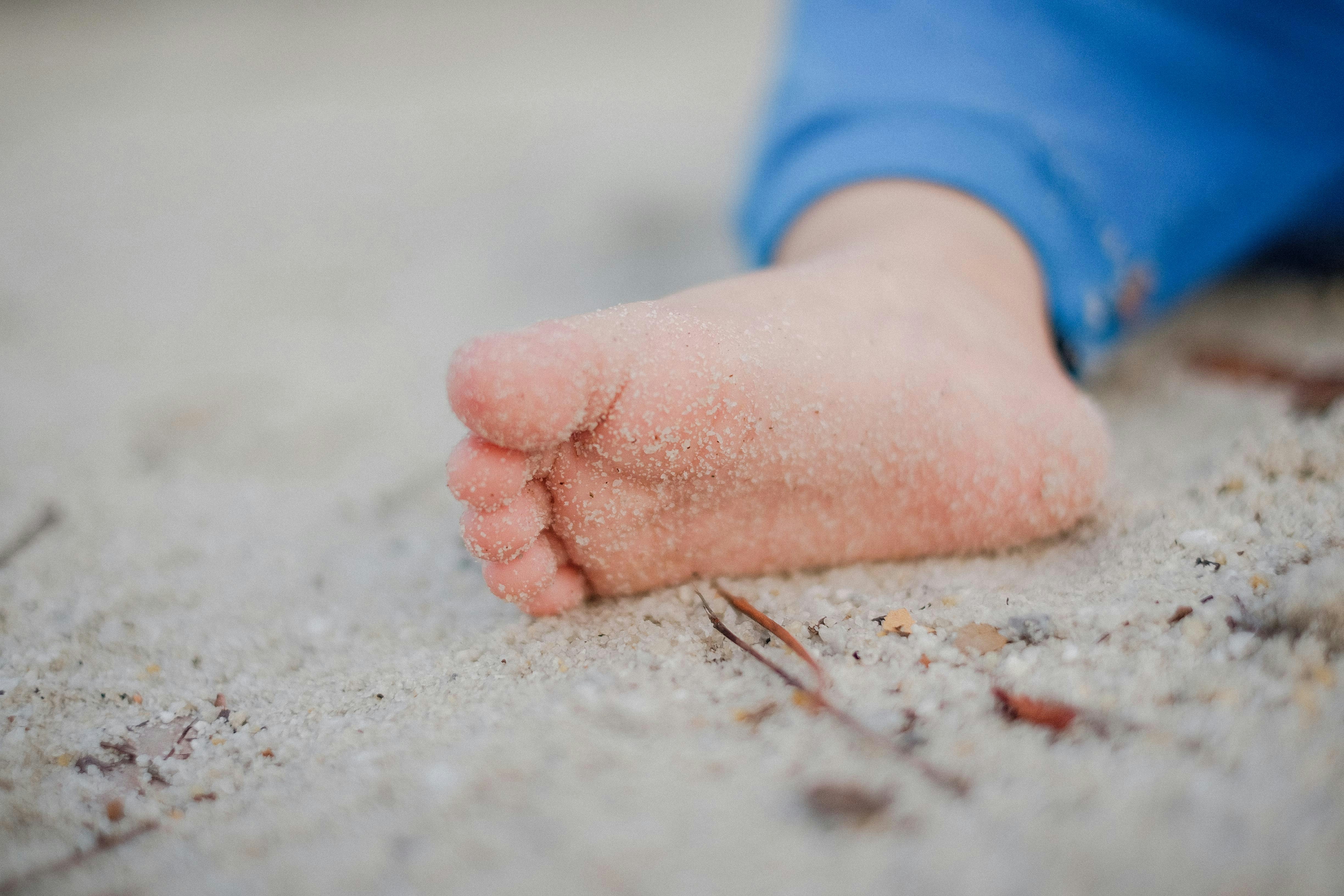 shallow focus photography of toddler's foot with sand