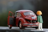 orange hair Lego toy looking at red beetle car