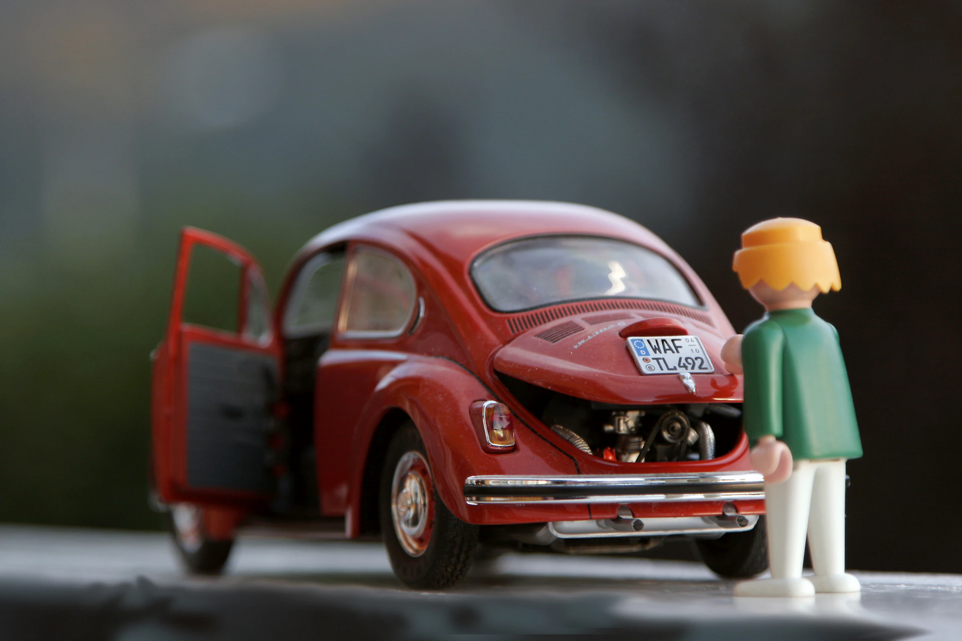 orange hair Lego toy looking at red beetle car