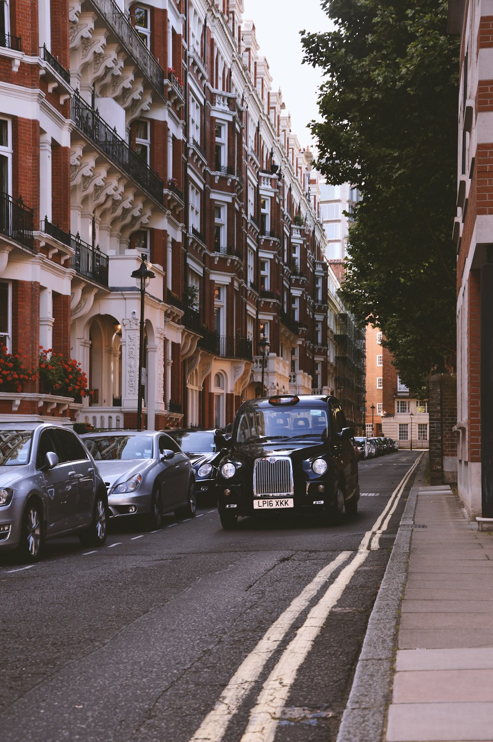 black vehicle arriving on grey concrete road between concrete buildings during daytime