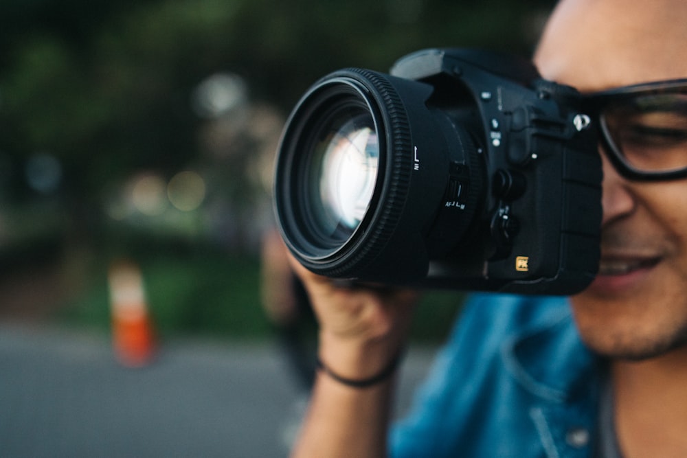 hombre sosteniendo una cámara DSLR negra