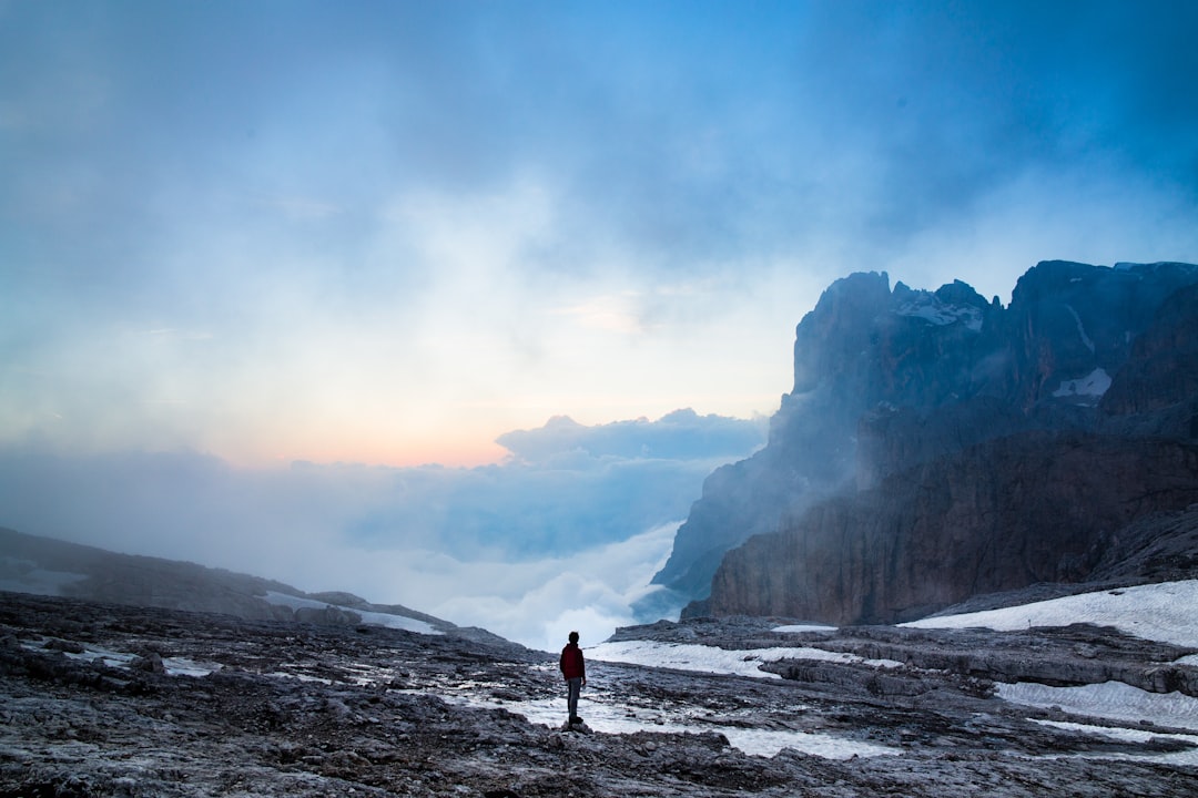 person standing near the cliff of the mountain, Hiker on a snowy slope