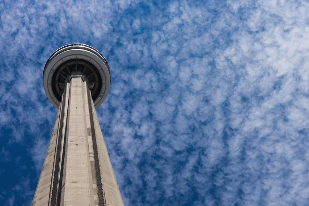 A low-angle shot of the tall CN Tower in Toronto against scattered clouds