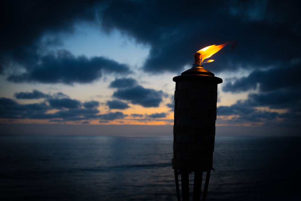 lighted tiki torch near sea at night