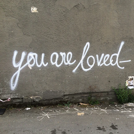 Close-up of a bright, hand-painted sign reading 'You are loved' displayed at a cuddles for our kids outreach program.