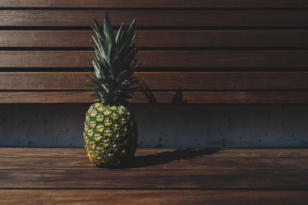 green and yellow pineapple placed on brown wooden pallet bench